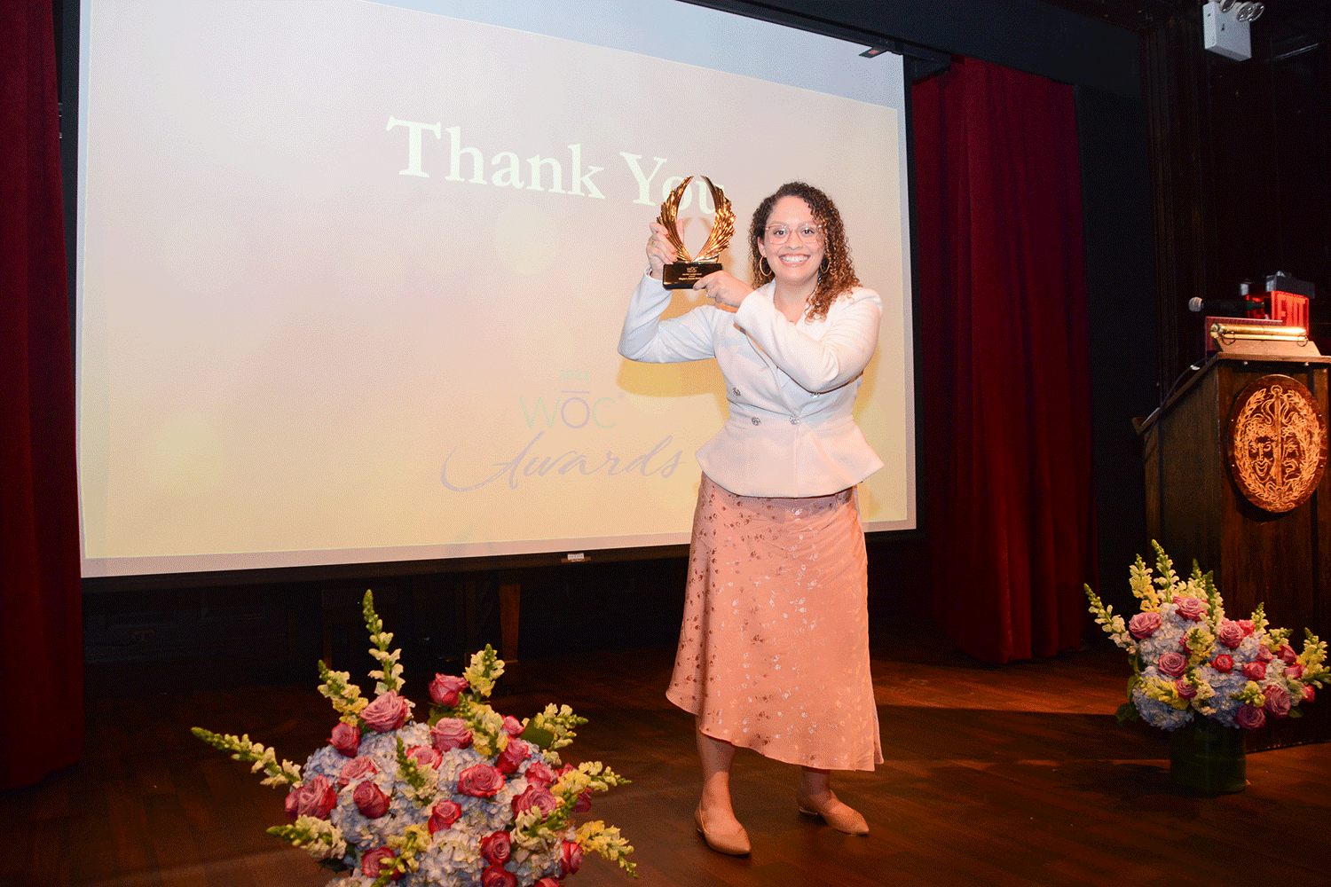 2023-woc-awards-megan-cerezo-mcmanus-holding-award-on-stage.png