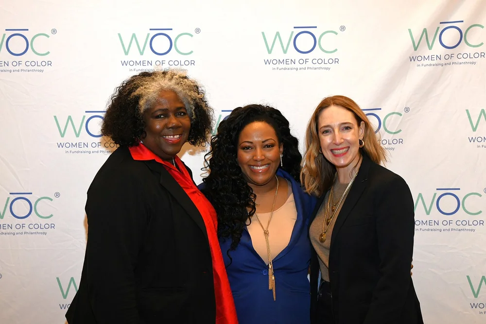 2024-woc-symposium-yolanda-f-johnson-poses-step-and-repeat-with-guests.jpg