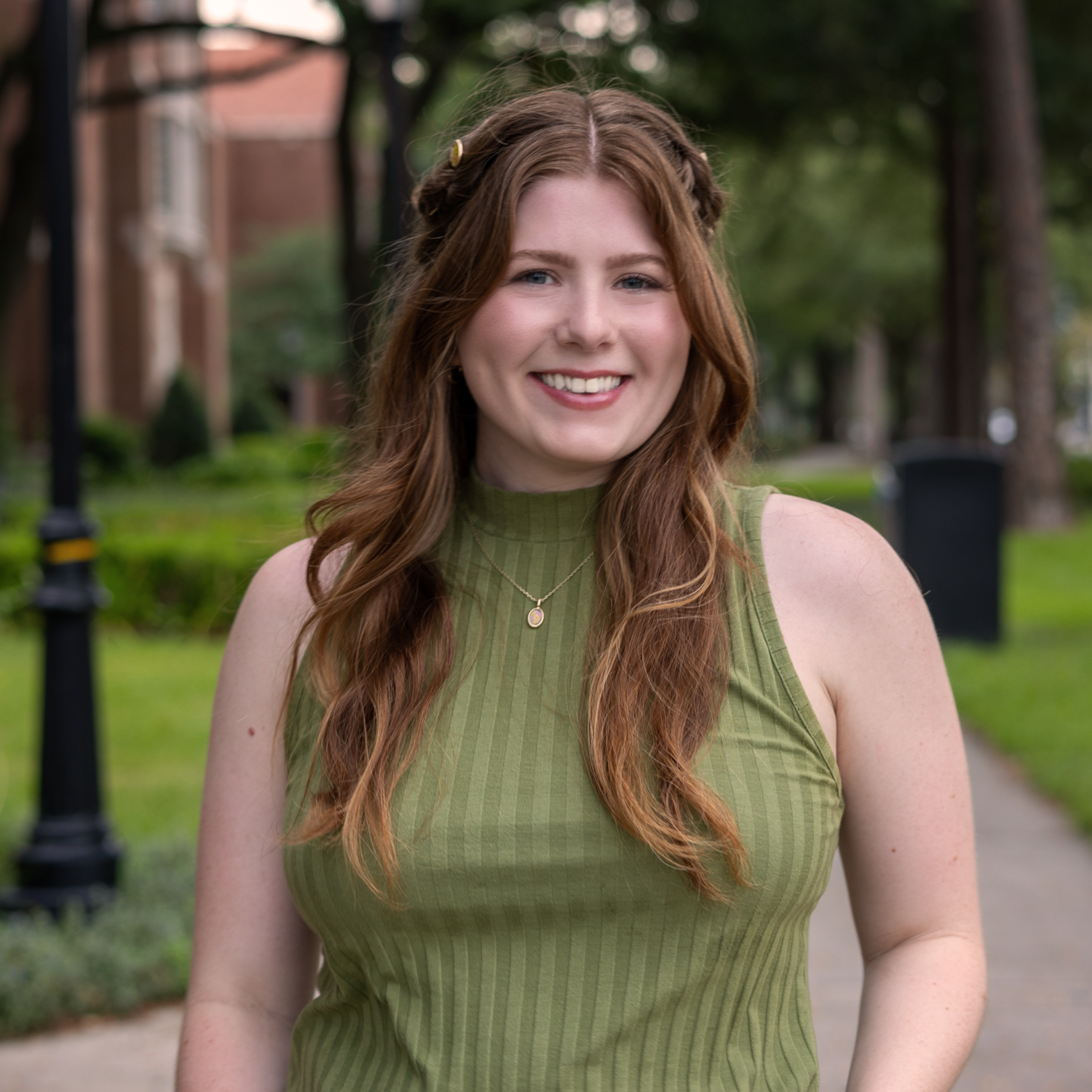 headshot of emily mcmahon-lynch in an outdoor setting, facing the camera, smiling, wearing a green top