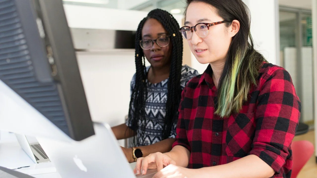 Two women wearing glasses looking at a computer. Photo by Christina Morillo.