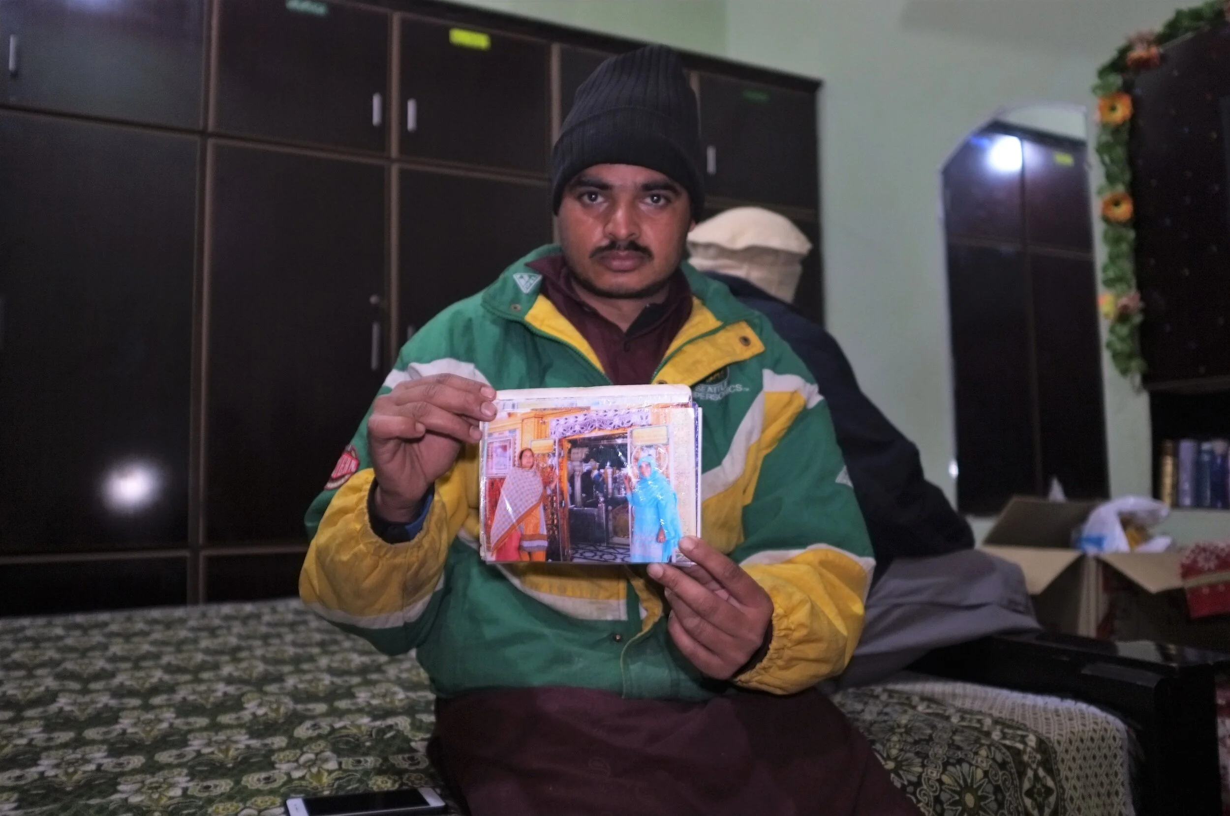 Babar holds a photo of his mother, Bilqis, held in a Saudi prison since 2017 (MEE/Suddaf Chaudry)