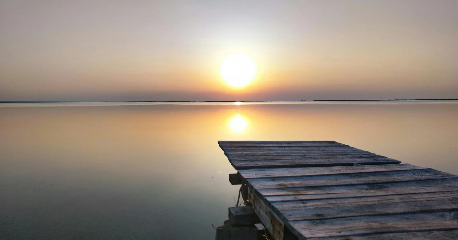 Sunrise over a calm water, symbolizing new beginnings and hope after setbacks.