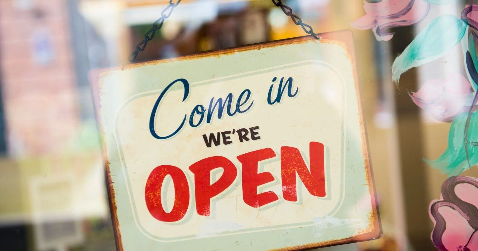 Sign in small business window saying come in we're open.