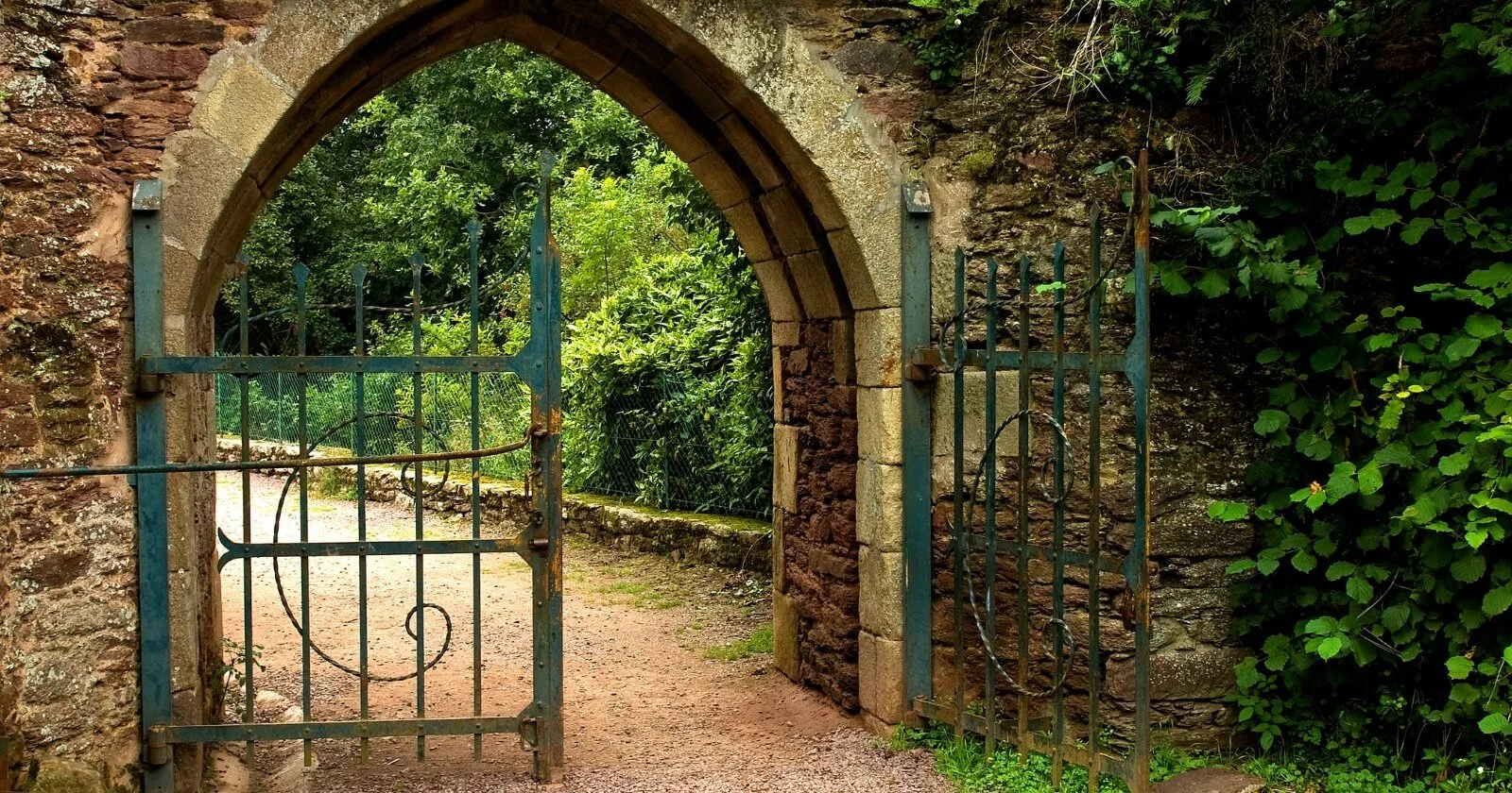 Stone wall blocking a path with a gate, representing limitations as guides to new directions.
