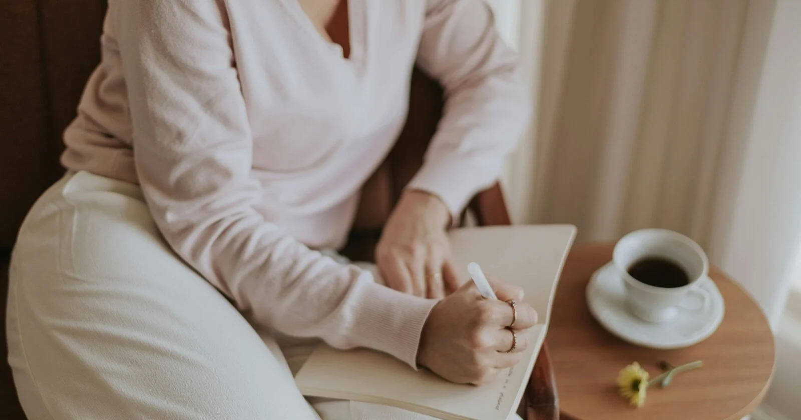 Person journaling at a desk in natural light, reflecting on thoughts and building self‑awareness.