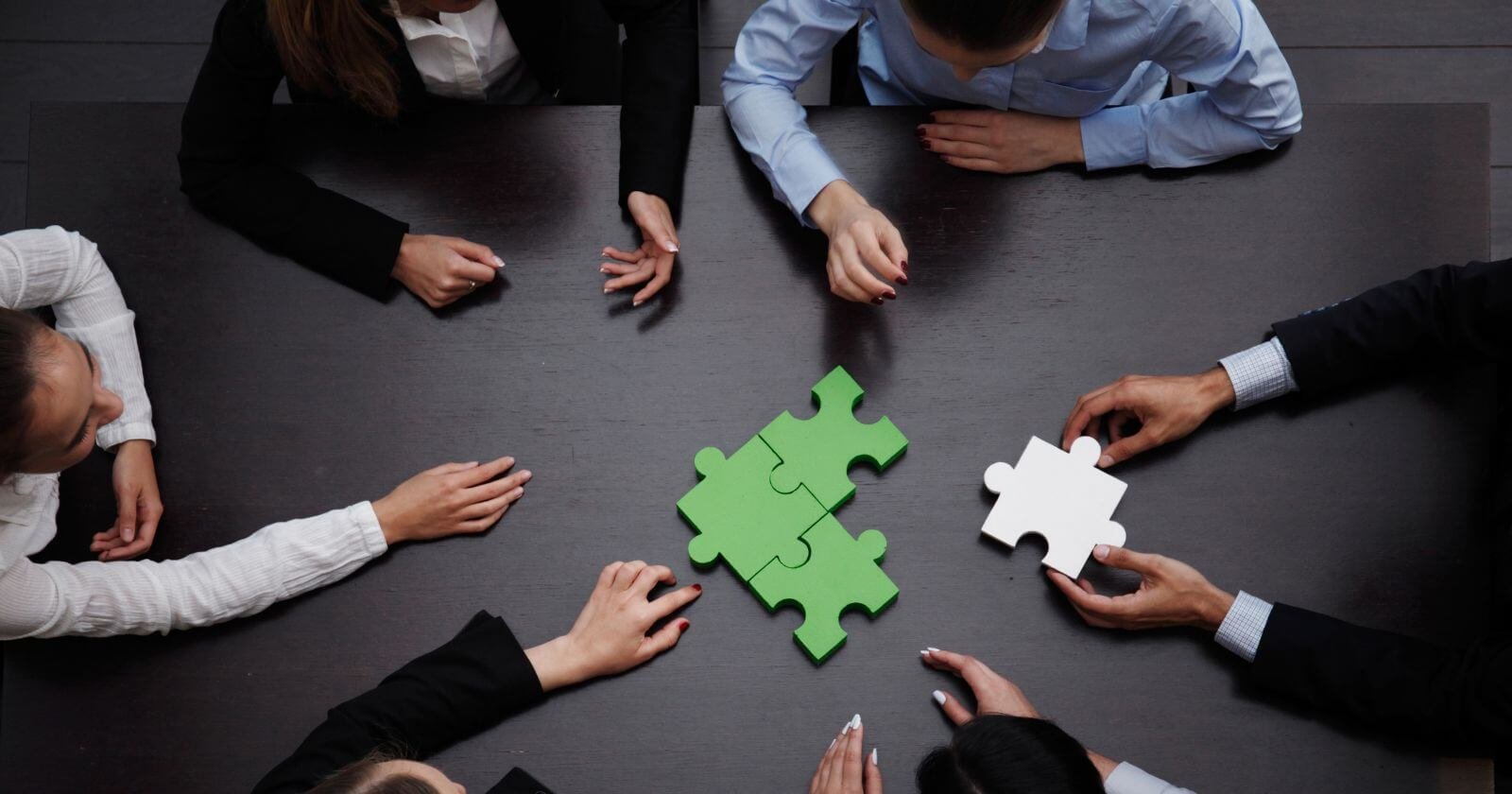 Business people putting a puzzle together demonstrating channel partner development.