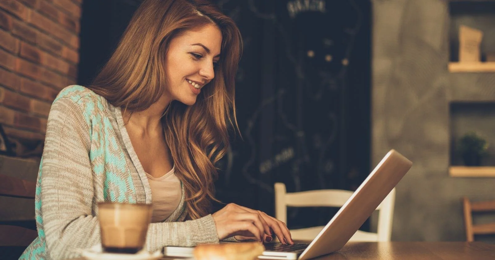 Woman blogging on her laptop in a cafe.