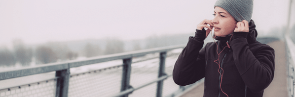 Woman in winter snow listens through headphones to her inner voice.