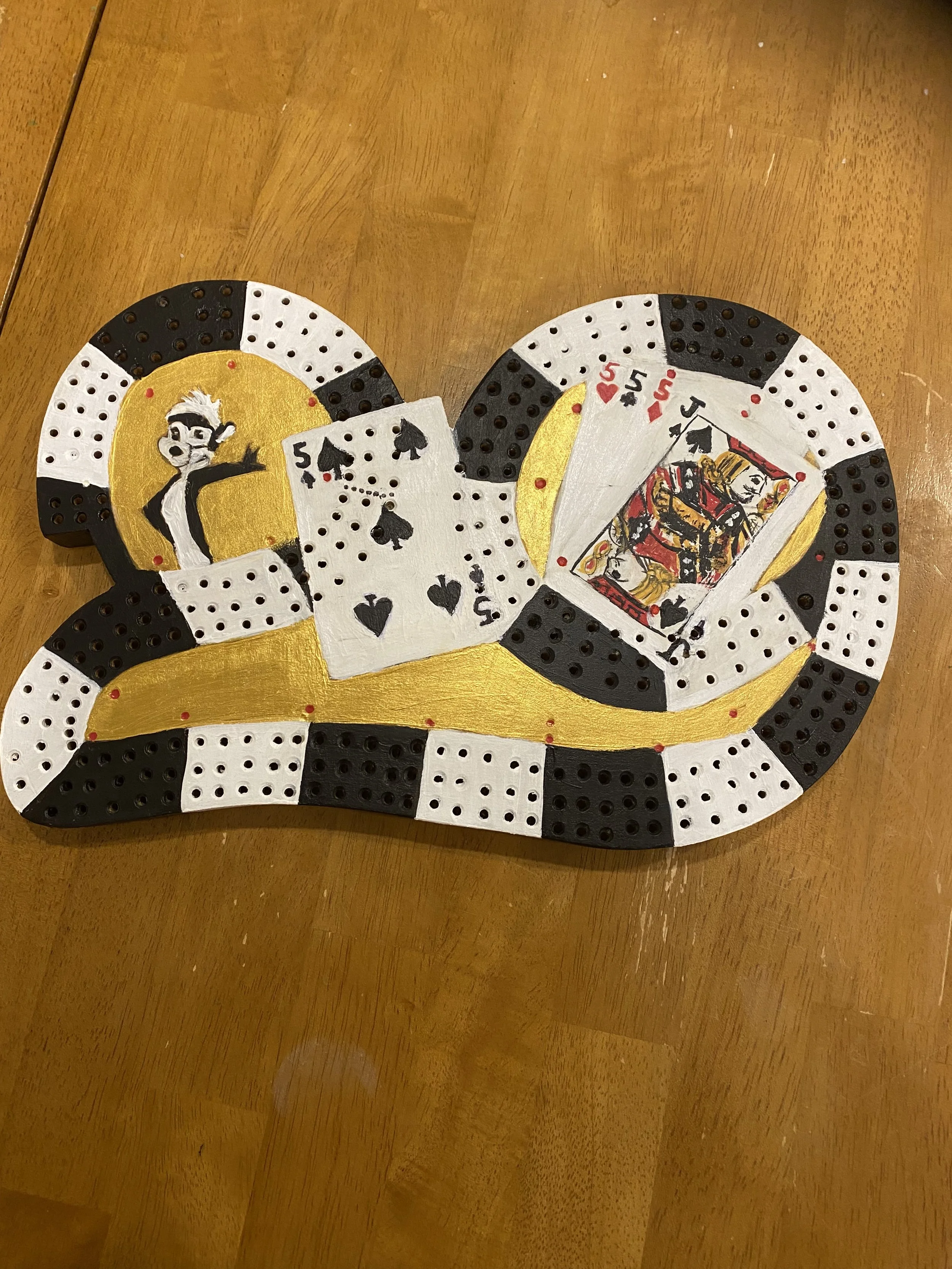 Handmade artwork resembling a snake, decorated with painted playing cards and poker chips, featuring a cartoon character and Queen of Spades.