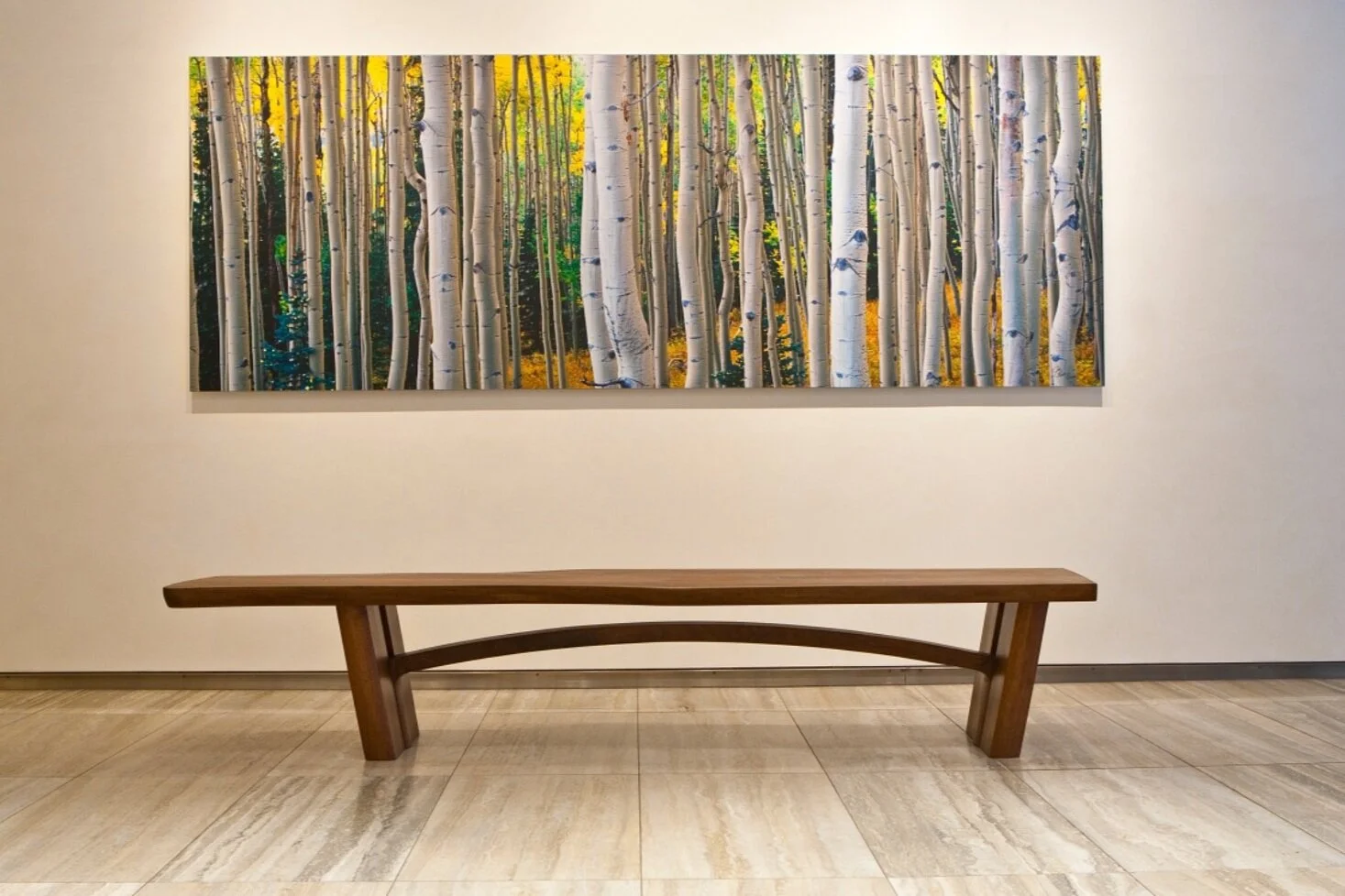 Custom wood furniture — a handcrafted bench with curved sculpted base in a modern living space