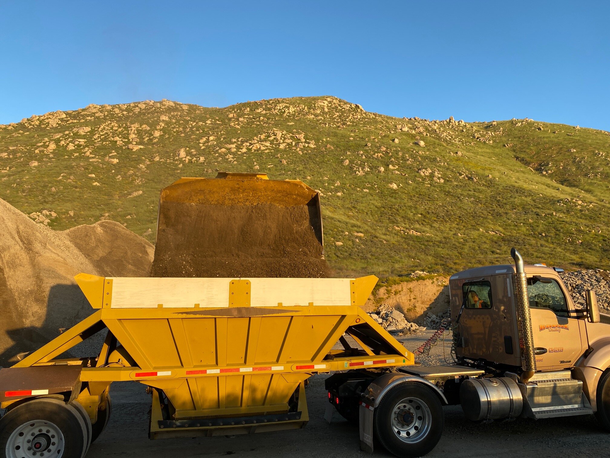 Road base being loaded in a bottom dump trailer