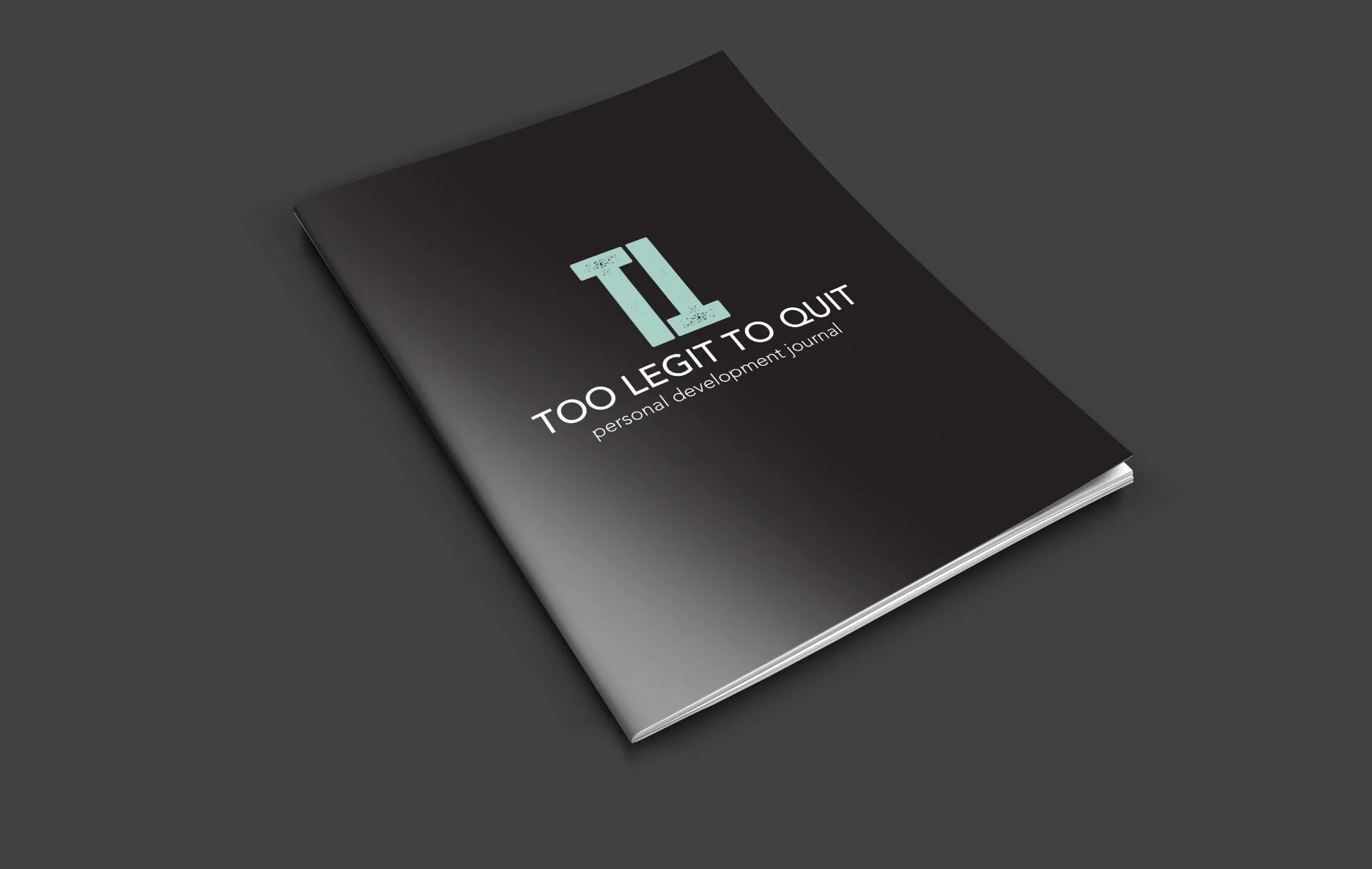 A black notebook titled 'Too Legit to Quit: Personal Development Journal' with a light blue 'TL' logo on a dark gray surface.