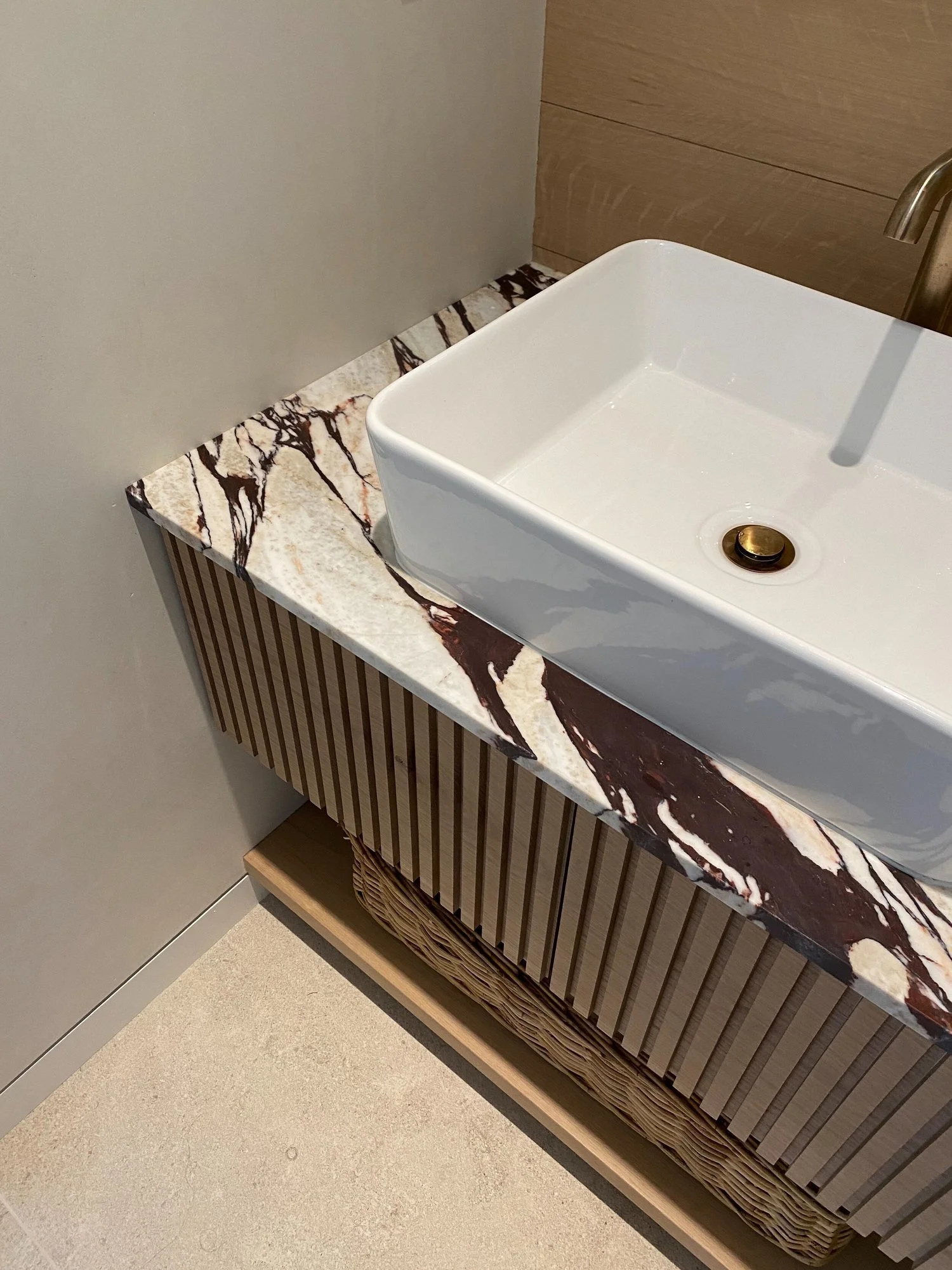 A bathroom vanity with a marble countertop and a white rectangular vessel sink with a chrome faucet.