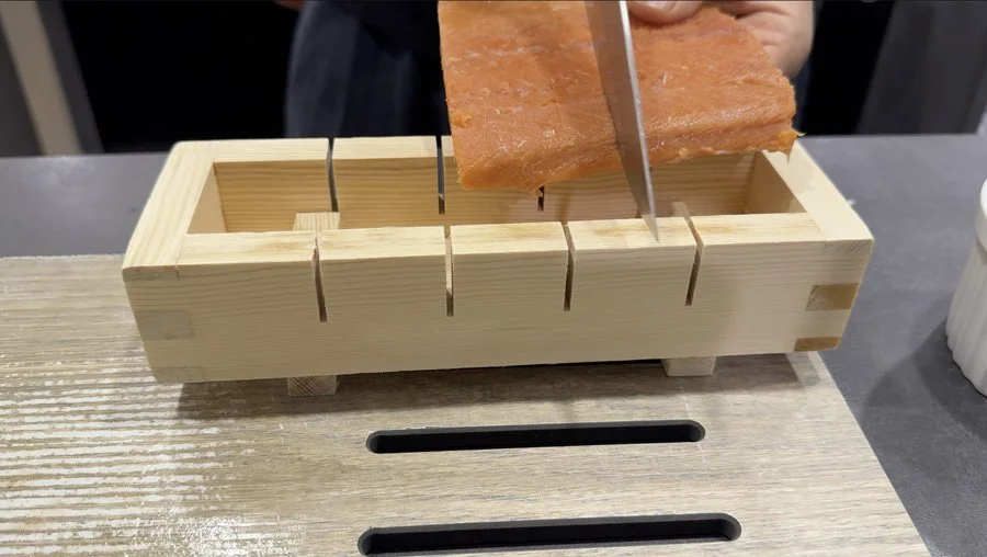 making slits into salmon using pressed sushi mold