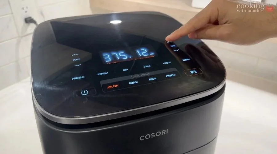 A hand sets the temperature and time on a COSORI air fryer to cook air fryer chicken breast at 375°F for 12 minutes.