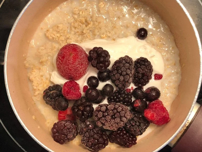 adding berries and yogurt to oatmeal