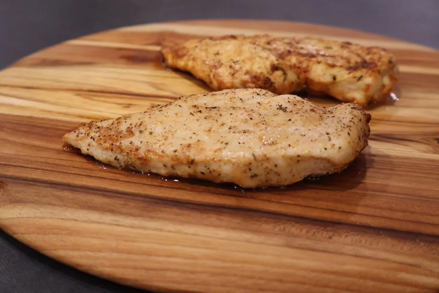 two juicy air fried chicken breasts on a board