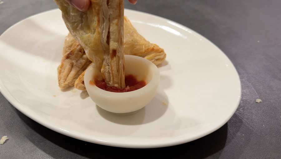dipping aloo puff patty in ketchup