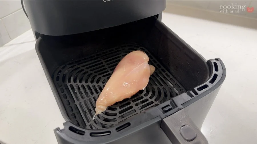 adding uneven chicken breast to air fryer basket