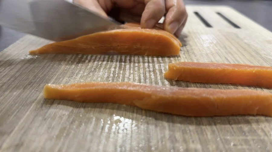 slicing long pieces of salmon