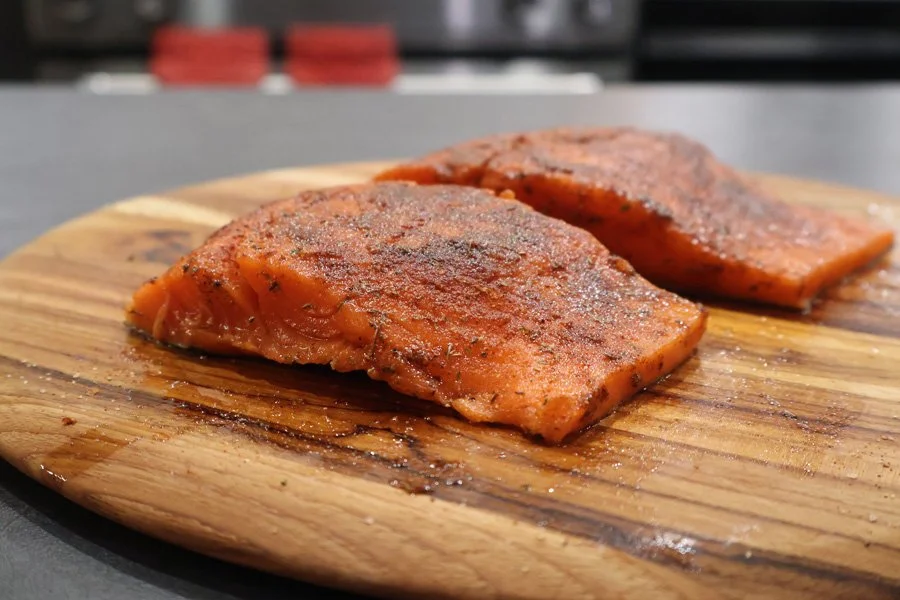 Two seasoned salmon fillets on a wooden cutting board, perfect for making delicious air fryer salmon.