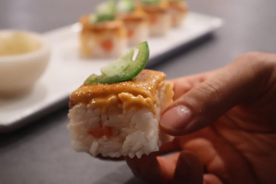 holding a piece of osaka style pressed sushi