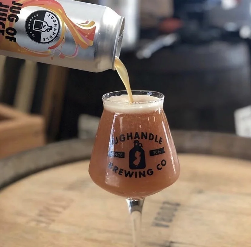 Jug of Juice beer being poured from an illustrated can into brewery glassware