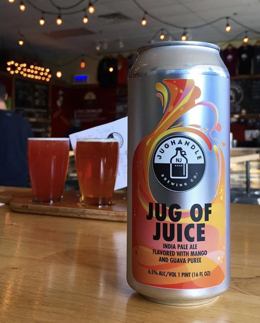 Jug of Juice can photographed on a wooden bar top with glasses in the background
