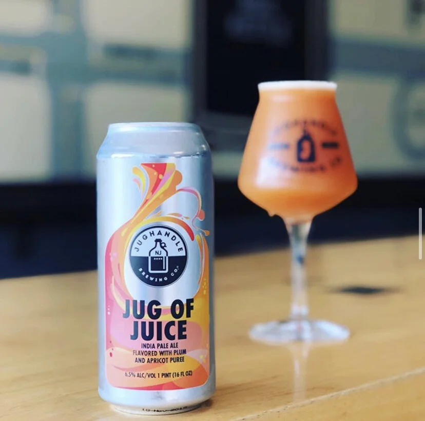 Jug of Juice silver can and hazy beer in a branded glass