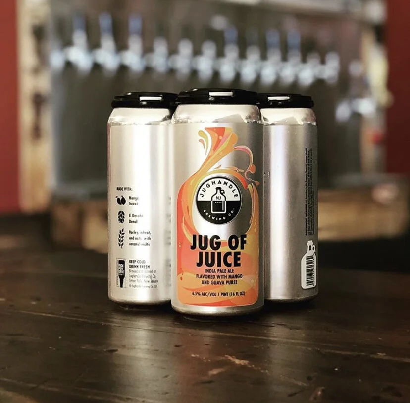 Three Jug of Juice cans arranged on the brewery bar