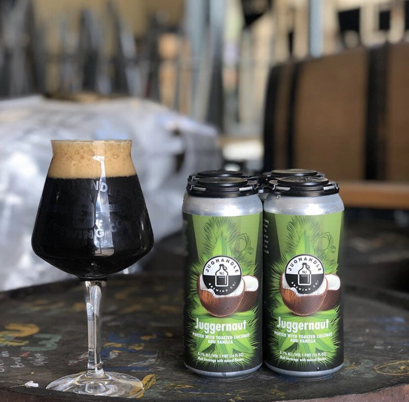 Two Juggernaut porter cans beside a dark beer in a glass
