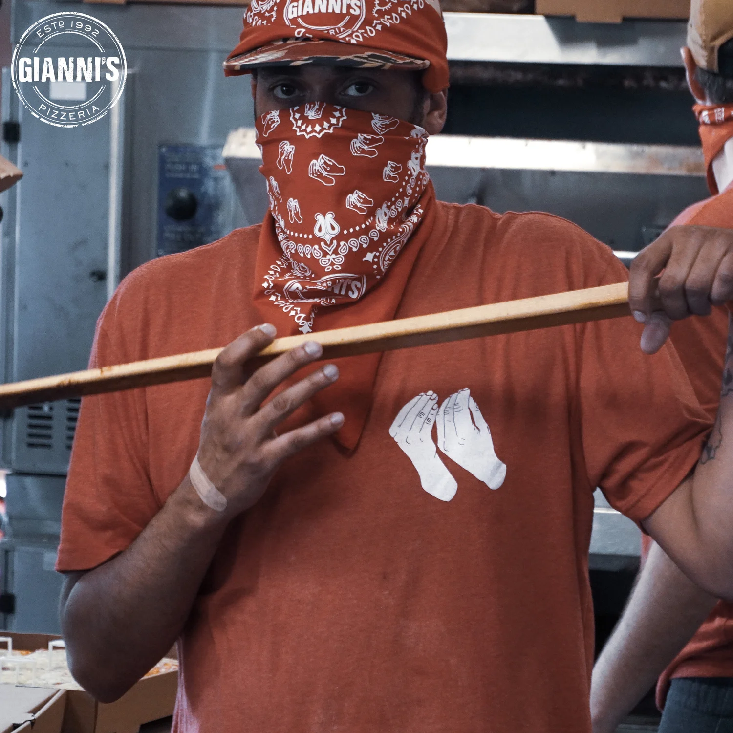 Gianni's Pizzeria staff member wearing branded bandana with identity artwork