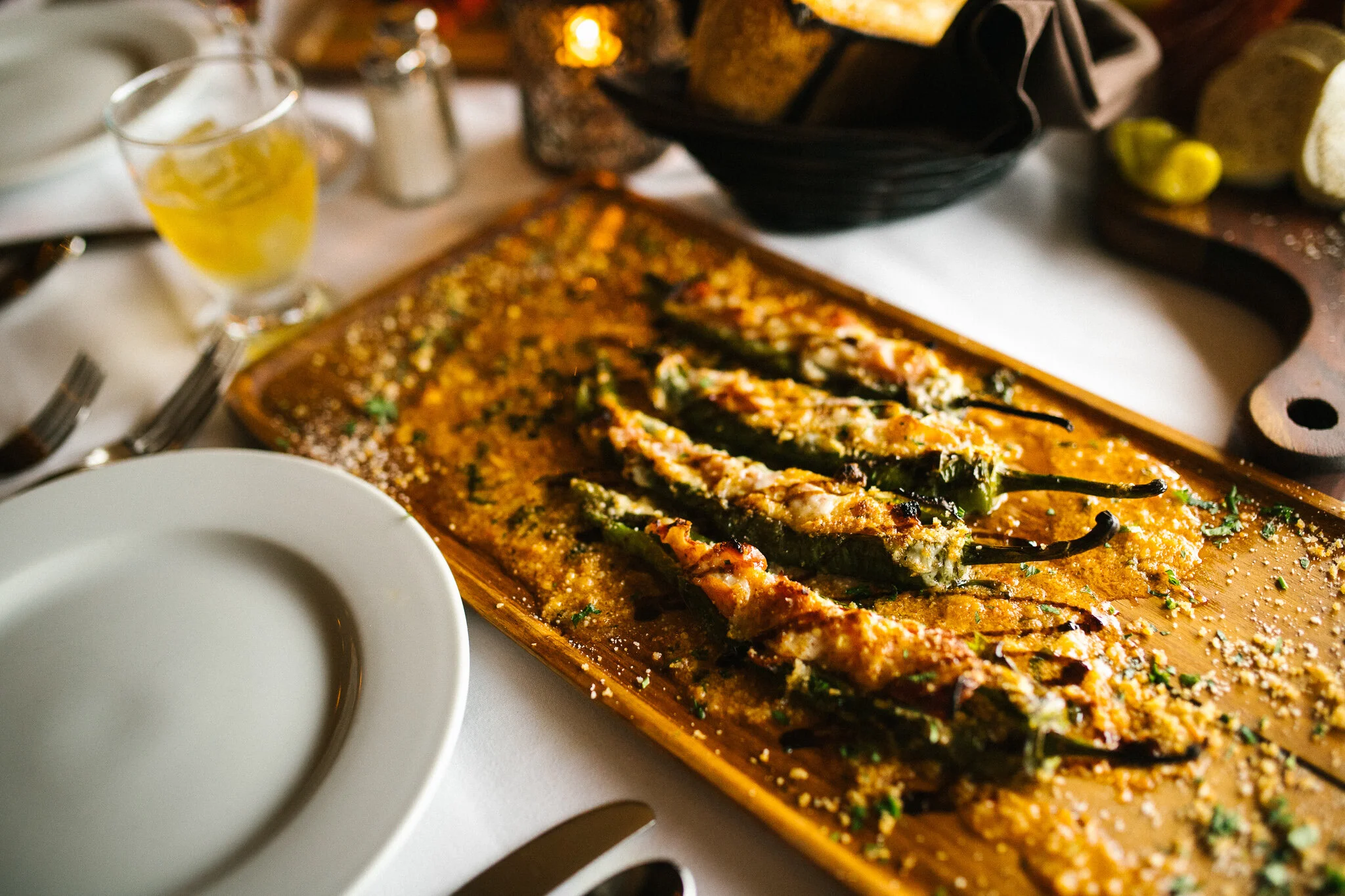 Roasted peppers and vegetables served on a wooden board with a warmly lit restaurant backdrop