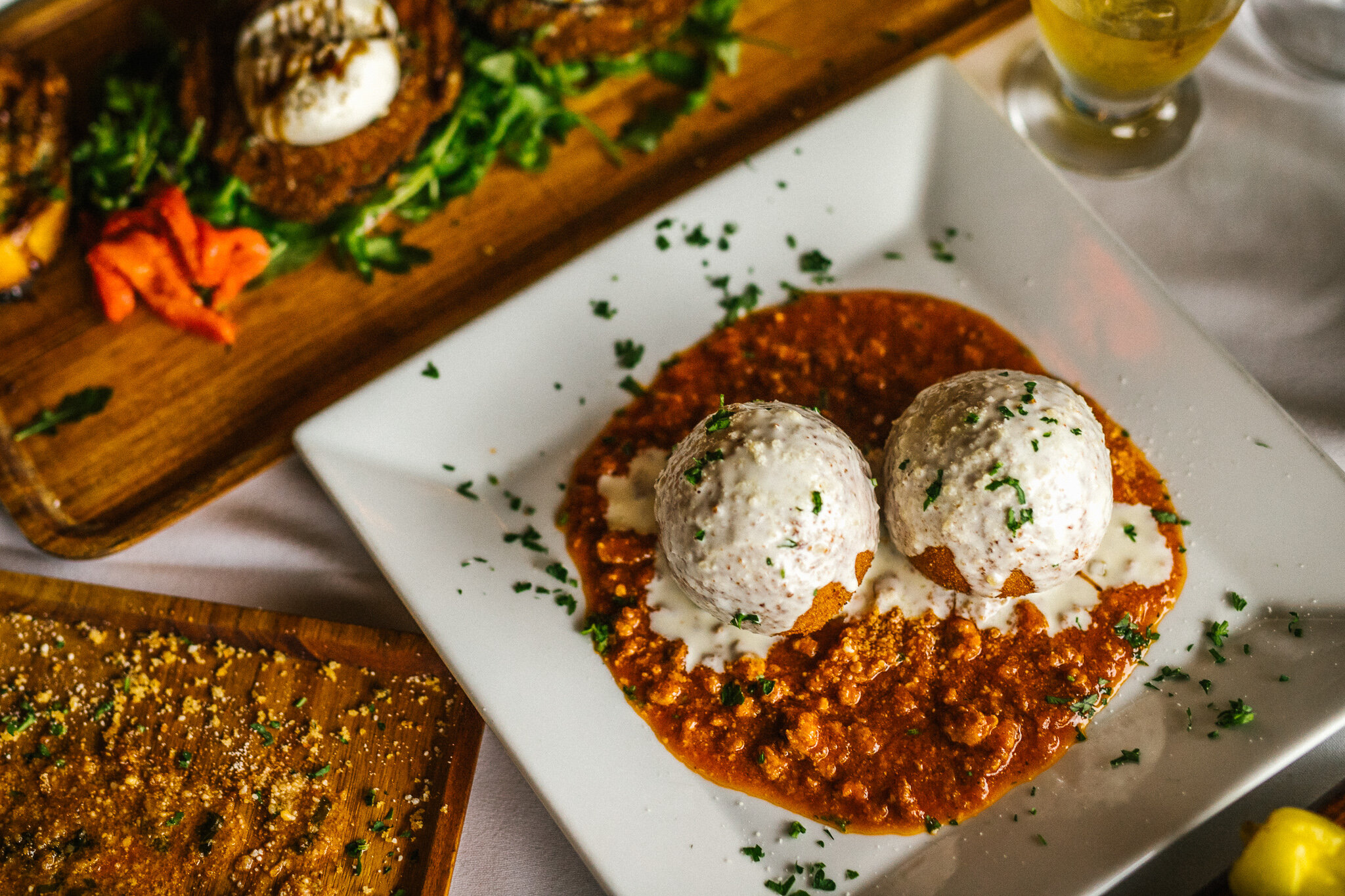 Two breaded Italian appetizers topped with white cheese over rich red sauce