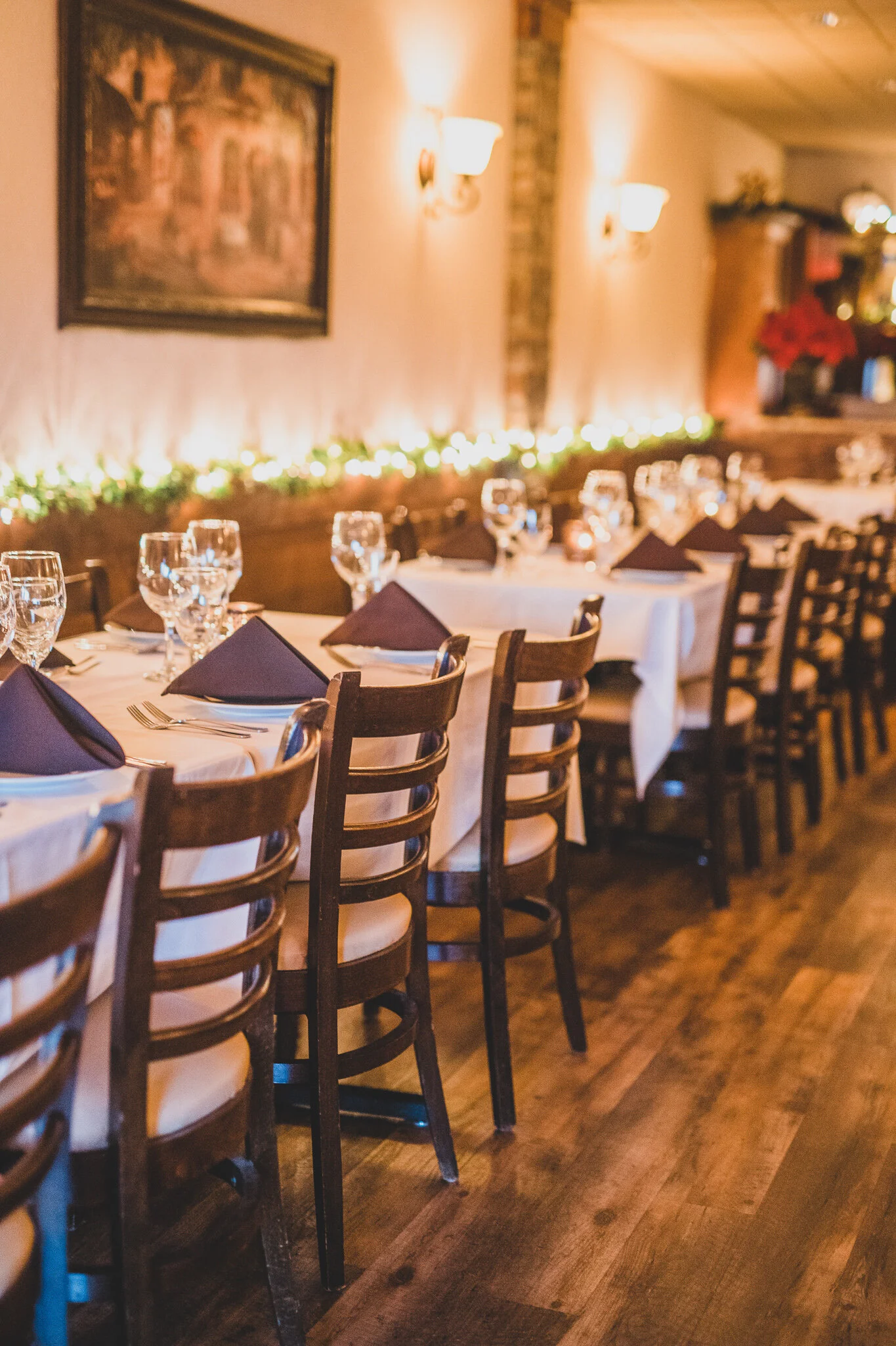 Warm Italian restaurant dining room set with tables, stemware and wood chairs
