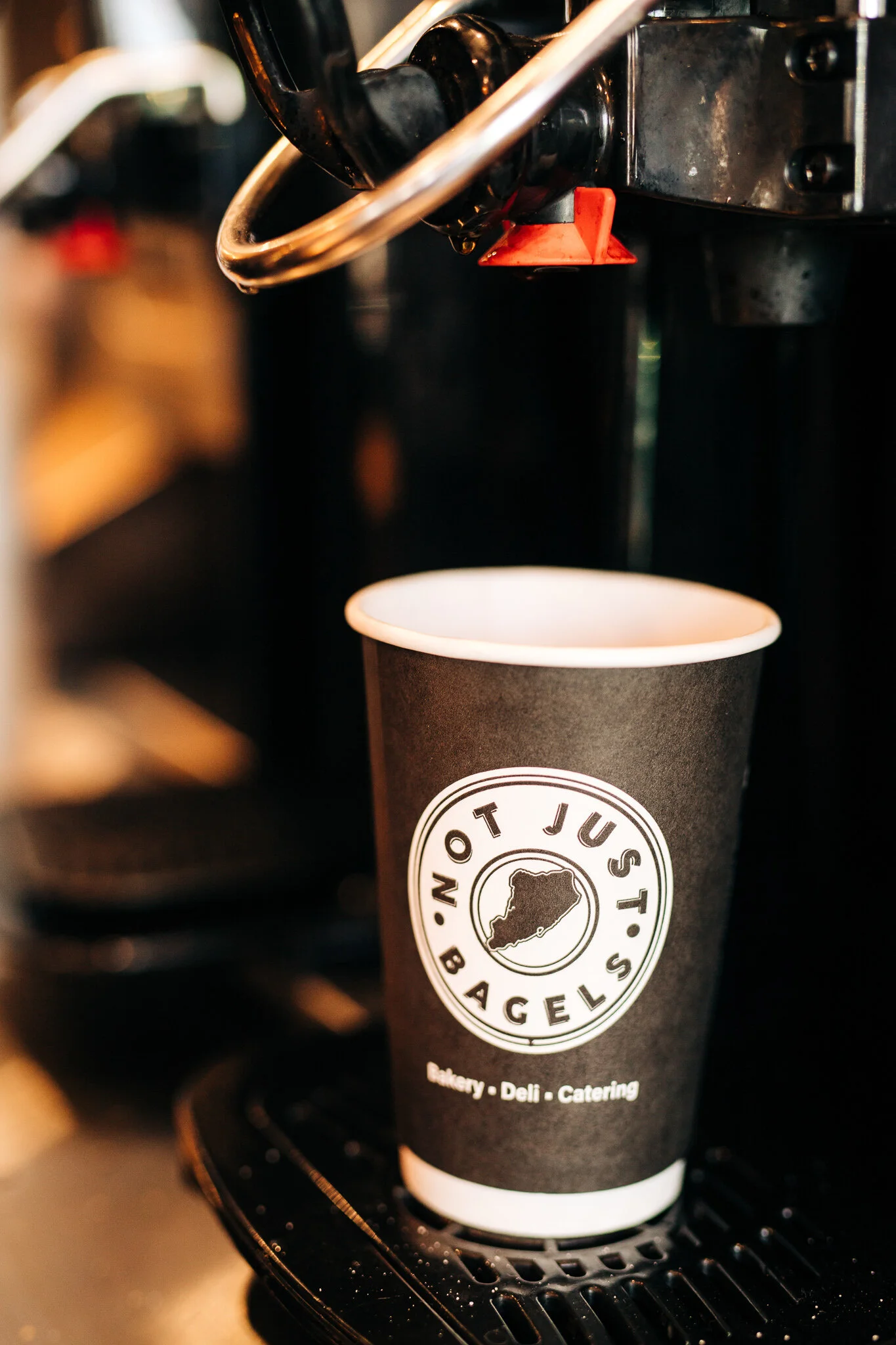 Branded Not Just Bagels takeaway coffee cup underneath the coffee machine