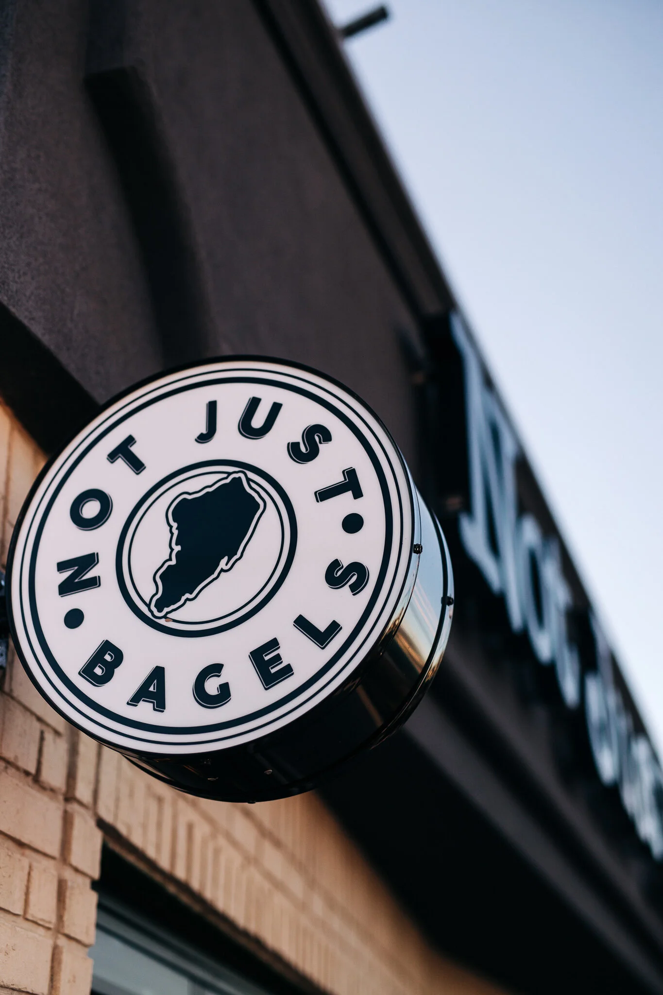 Round Not Just Bagels exterior blade sign mounted at storefront