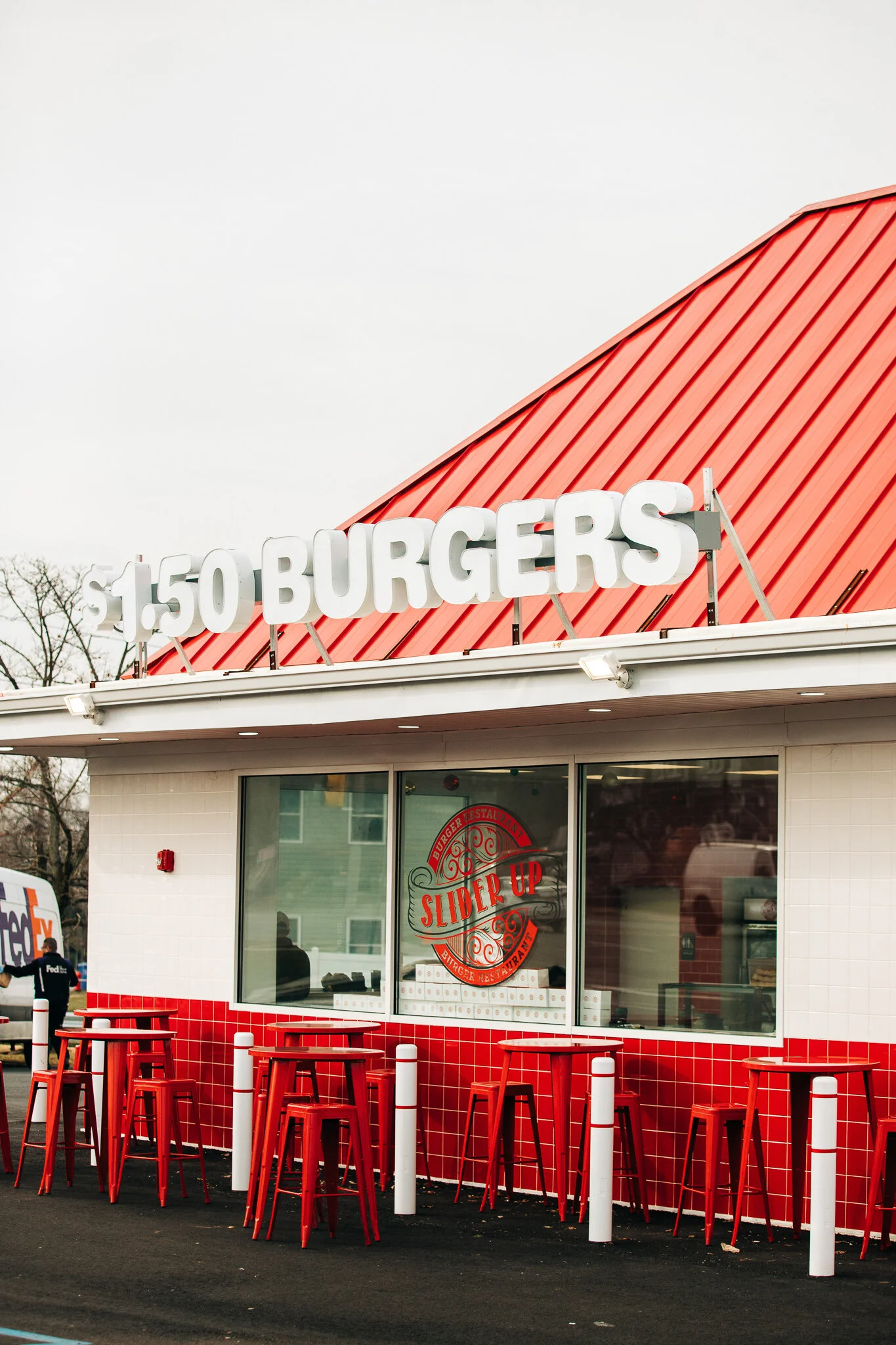 Slider Up Burger Restaurant white and red storefront with exterior counter stools and dollar-fifty burger lettering
