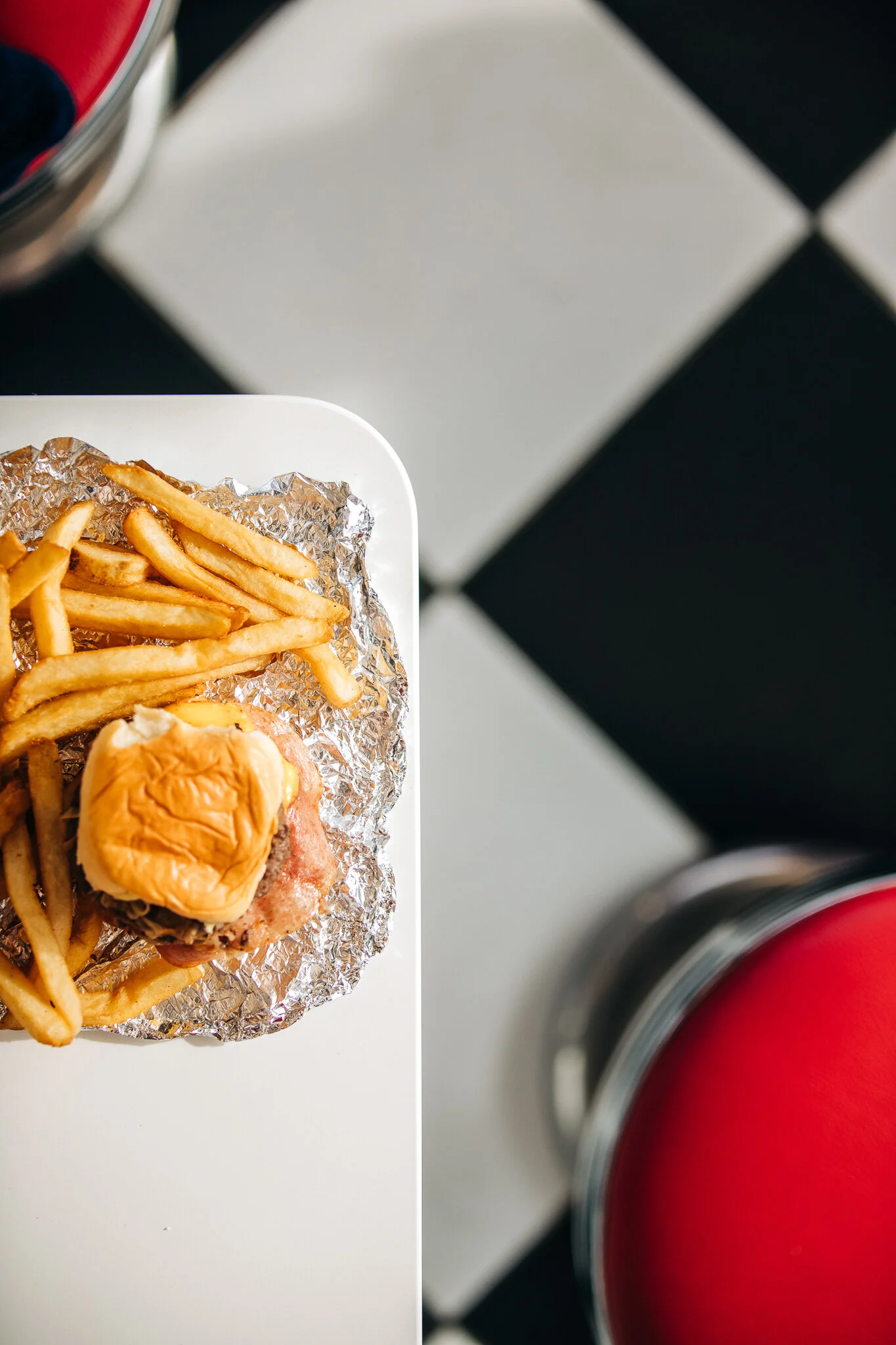 Overhead restaurant photography of a wrapped Slider Up burger and french fries against a black and white checkerboard floor