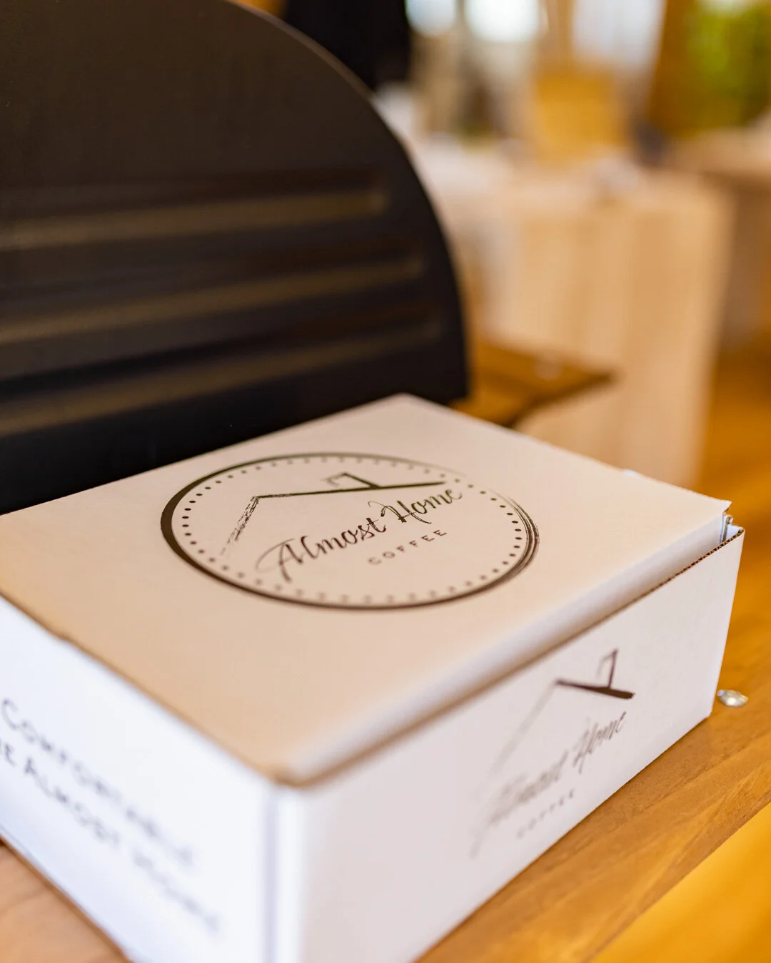 Almost Home Coffee logo featured on white branded packaging