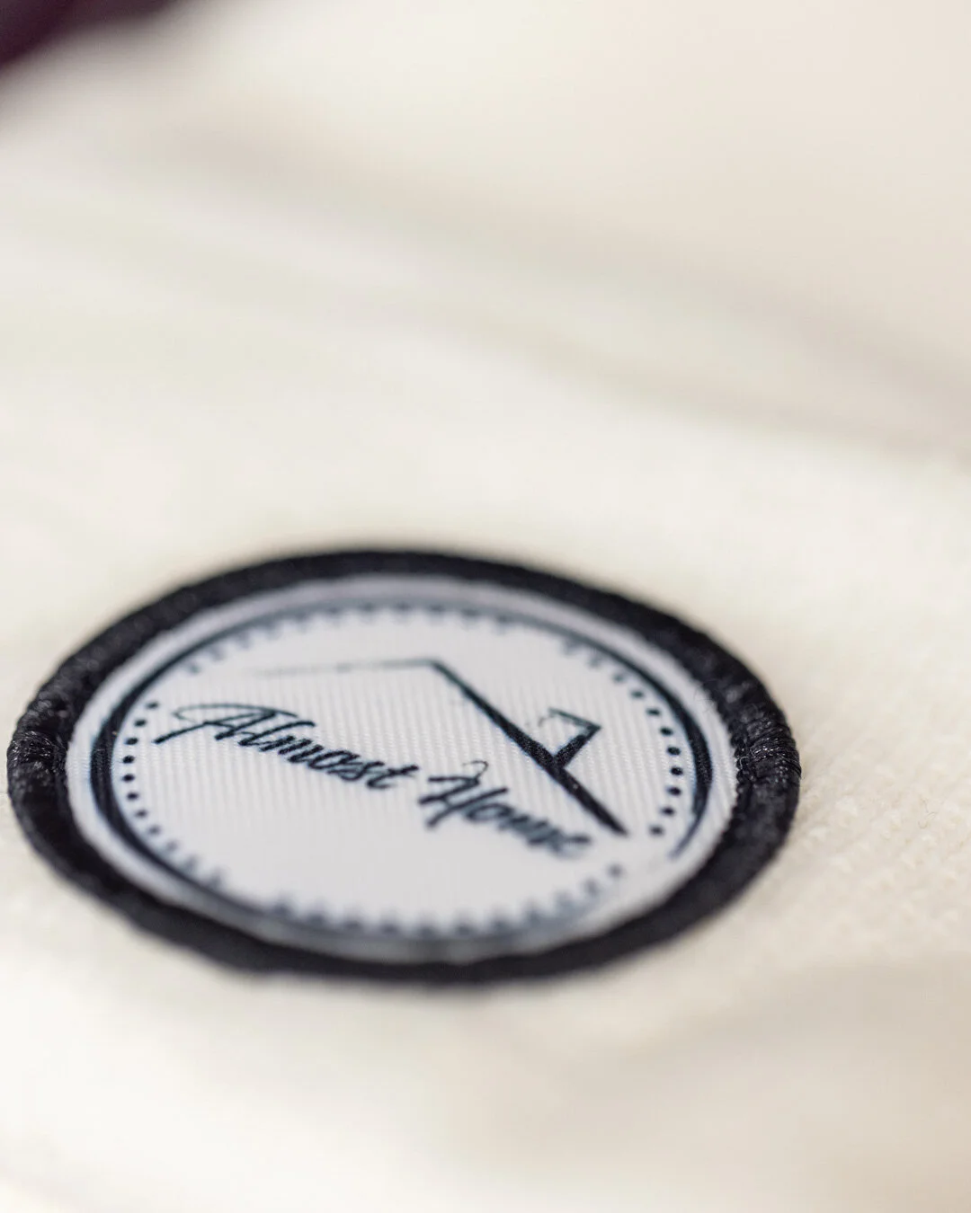 Circular embroidered Almost Home Coffee brand patch on fabric
