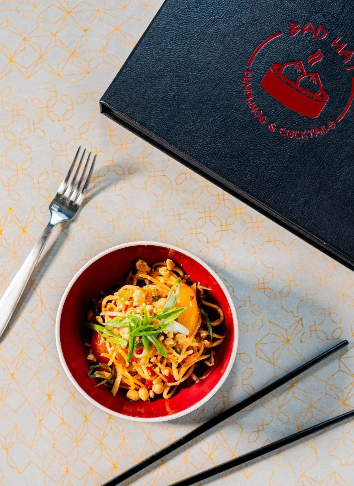 Bad Hat printed menu photographed on a tabletop alongside a plated dish