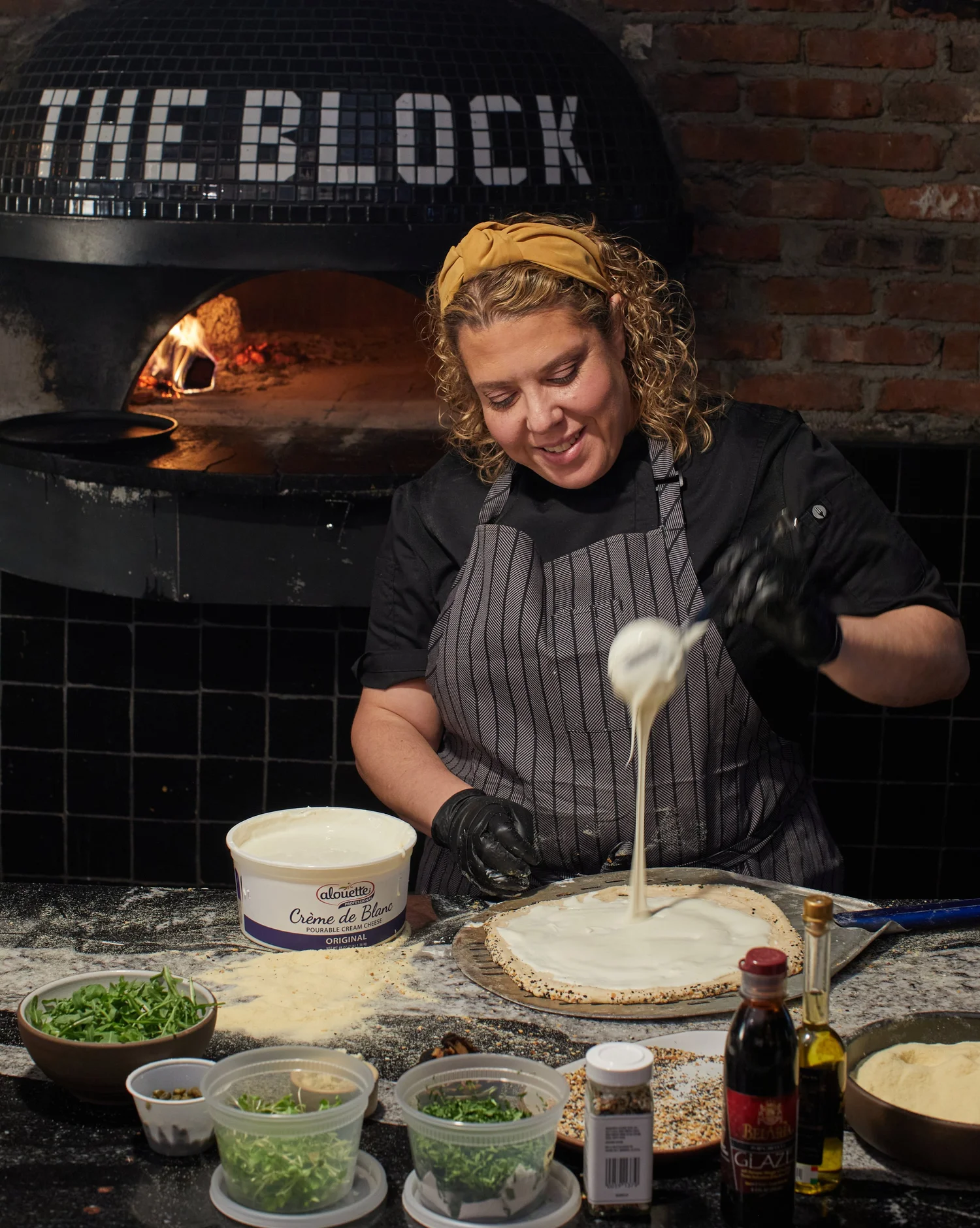 Cheese being applied to pizza dough