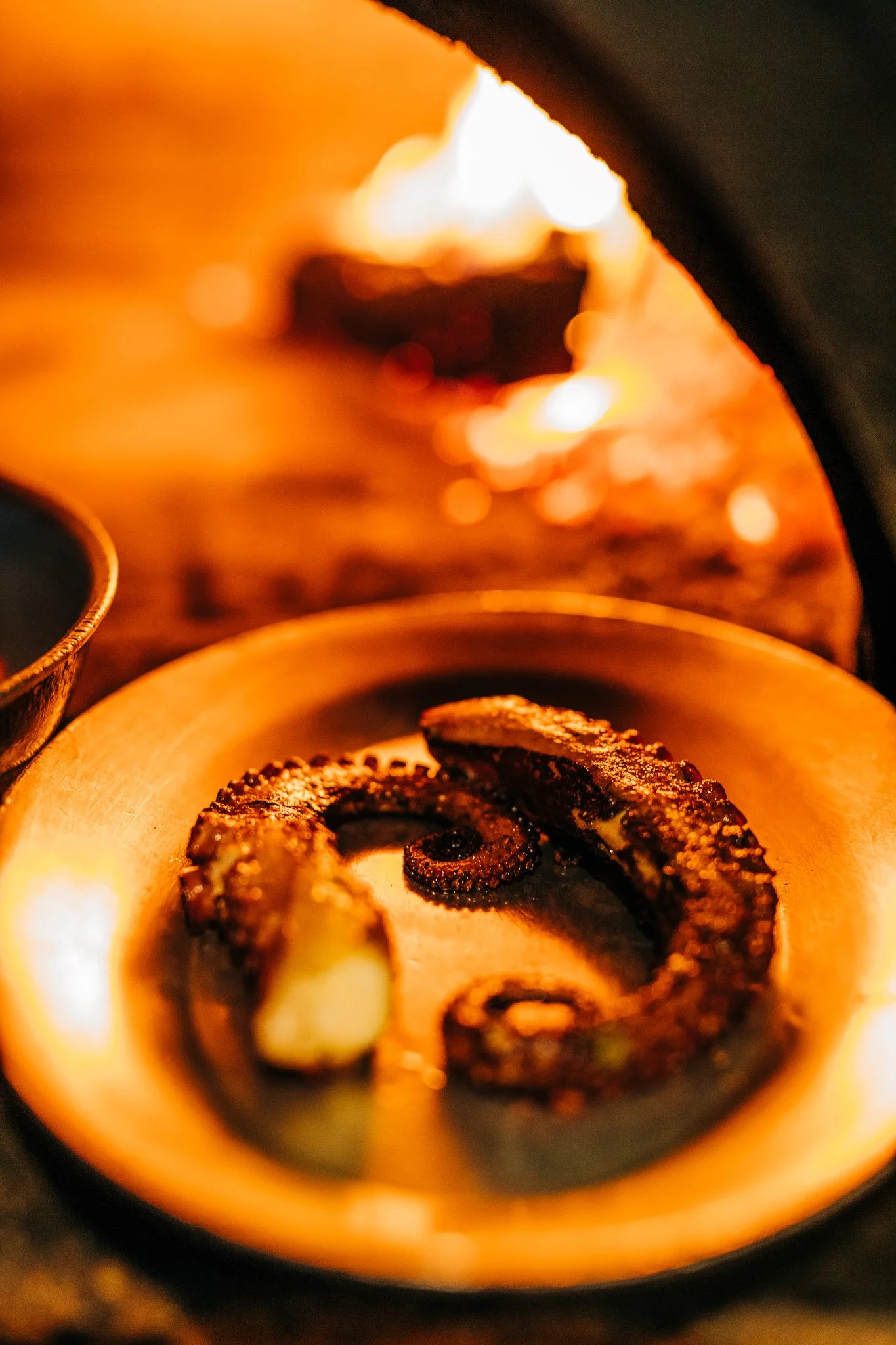 Grilled octopus photographed near a wood-fired oven