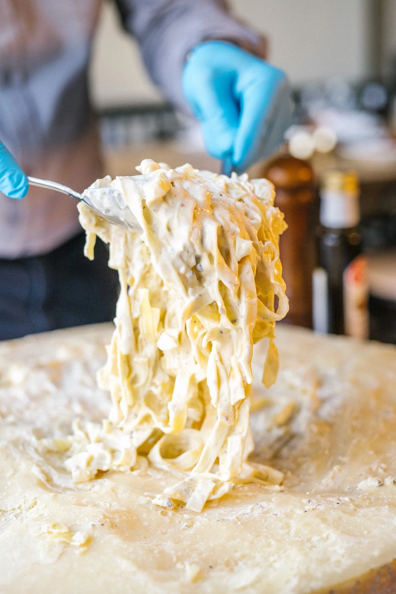 Fresh fettuccine being lifted from a cheese wheel
