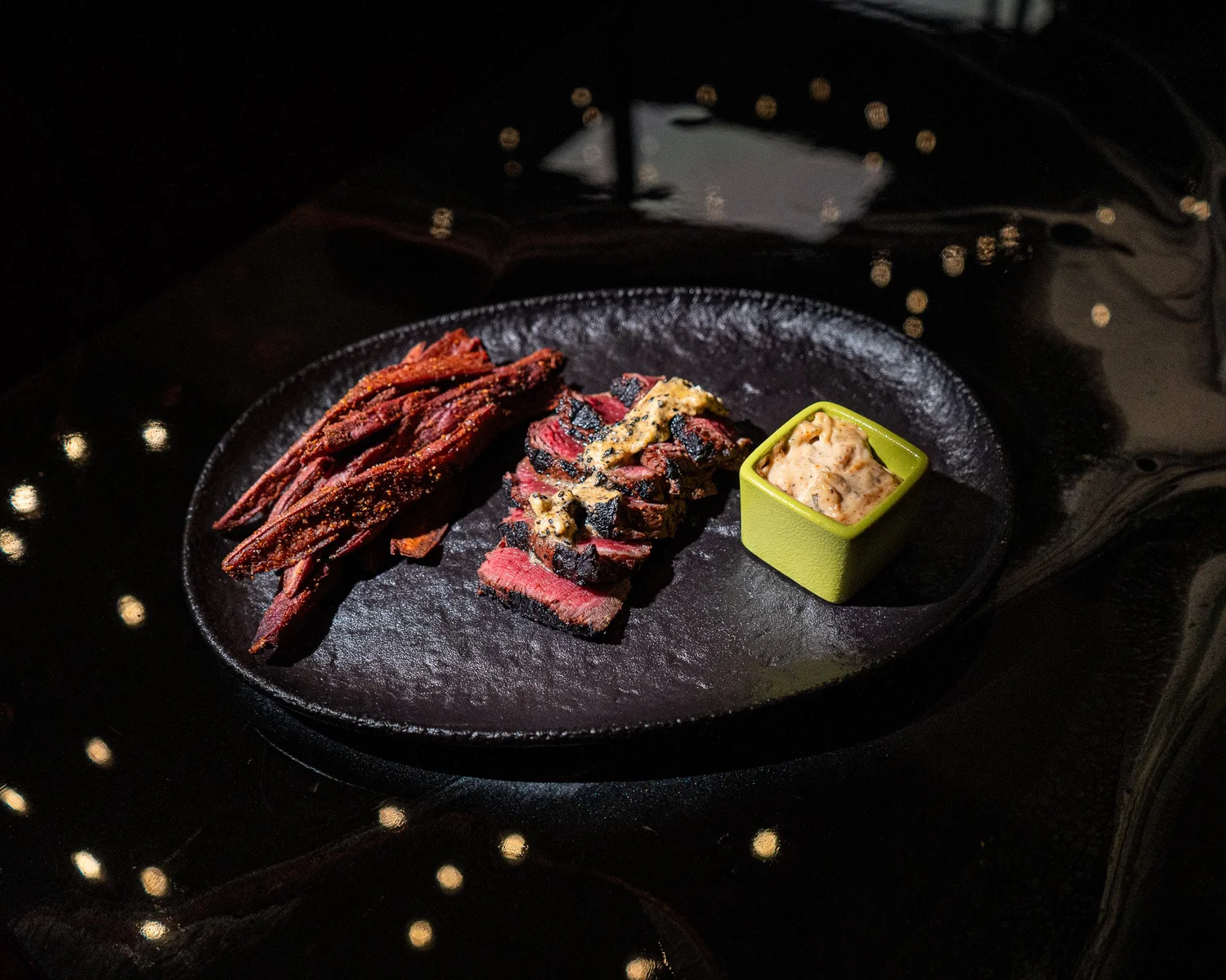 Sliced meat and vibrant garnish arranged on a dark serving plate