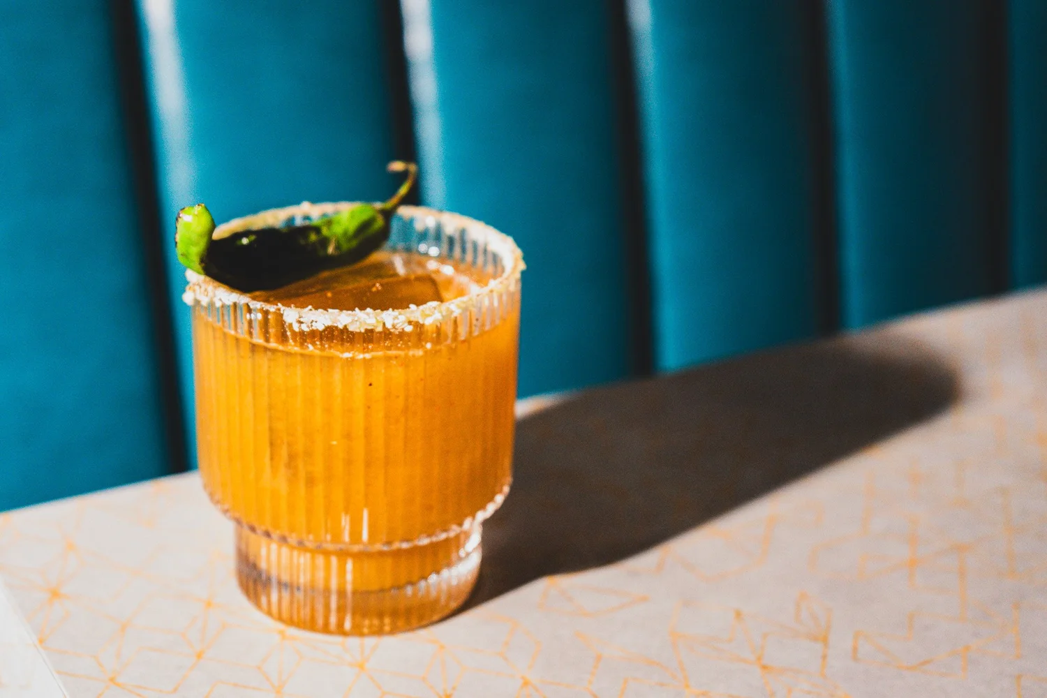 Orange cocktail with a salted rim and green garnish