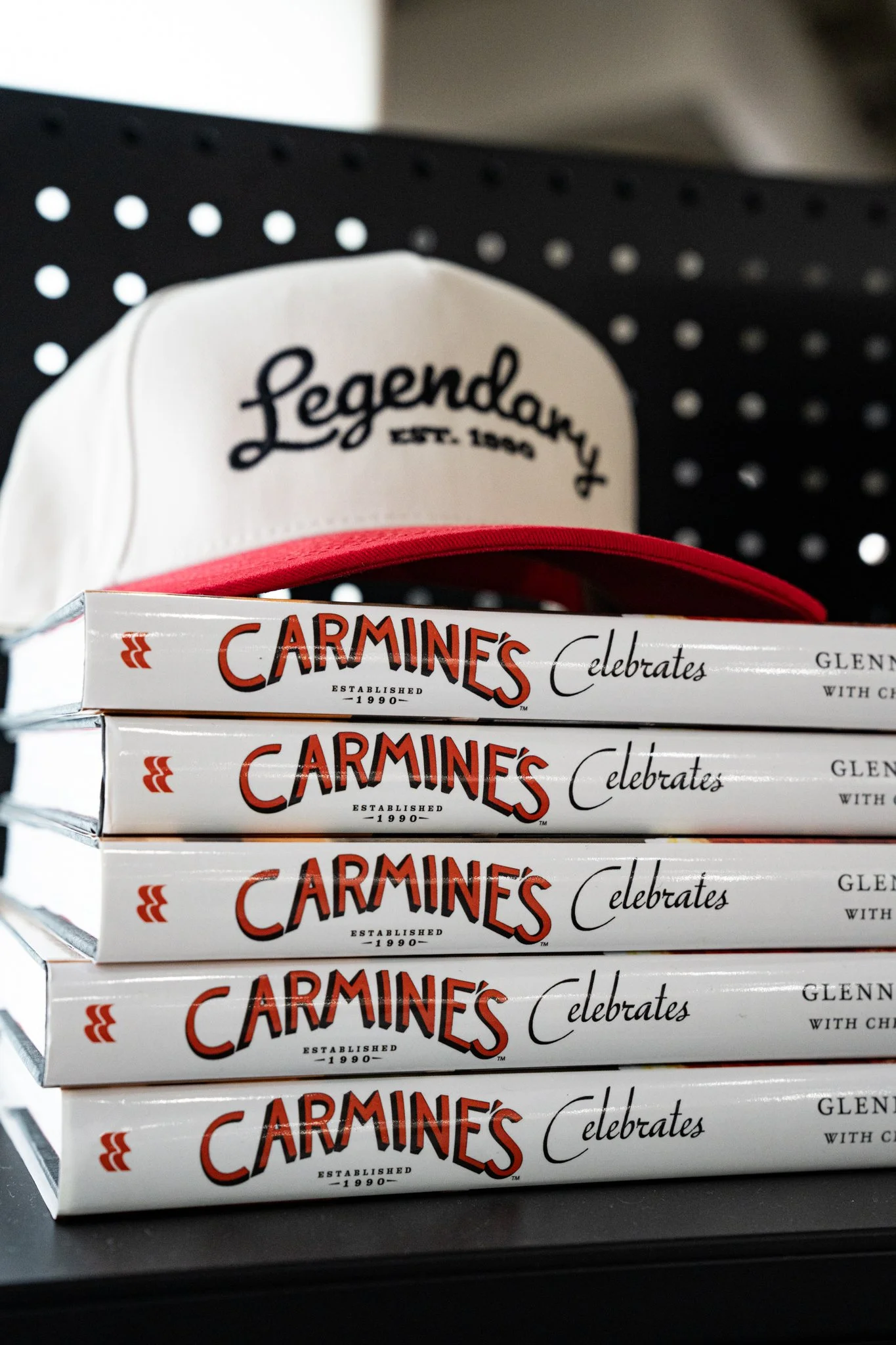 Carmine’s branded cap and cookbooks photographed at a specialty food show