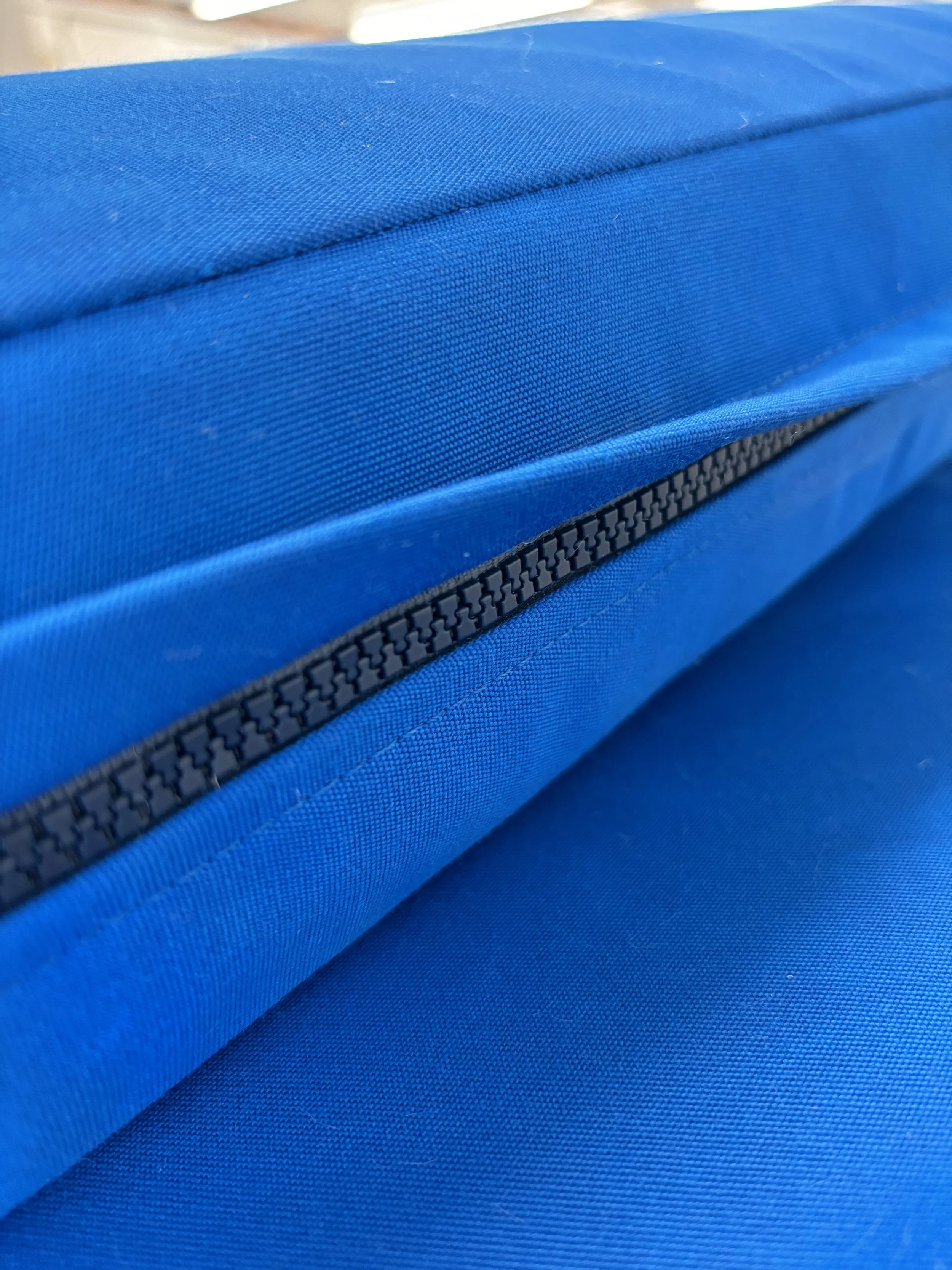 Close-up of a blue fabric bag with a black zipper.
