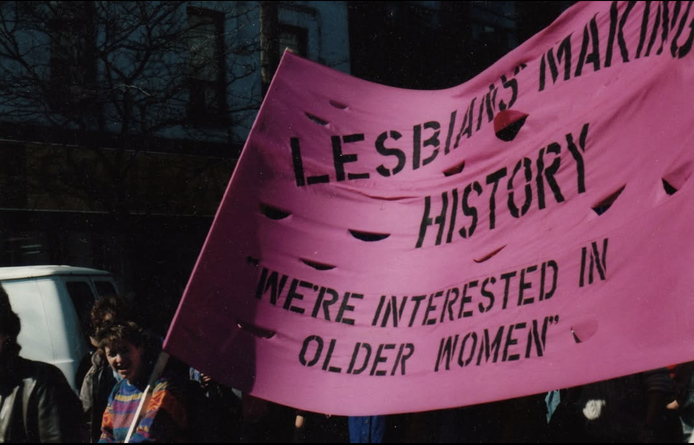 Pink protest banner with text 'Lesbians Making History, We're Interested in Older Women', The Arquives Toronto LGBTQ+